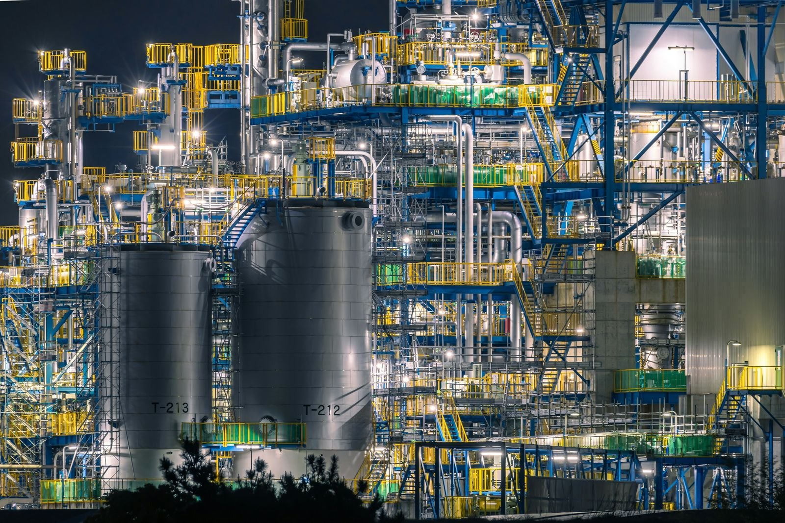 Petrochemical refinery complex with distillation columns and storage tanks illuminated at night
